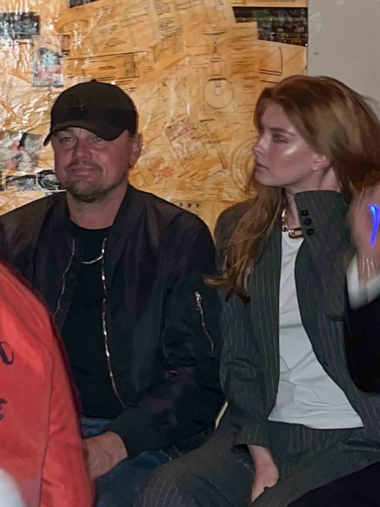 Leonardo DiCaprio in a black outfit with a mysterious woman